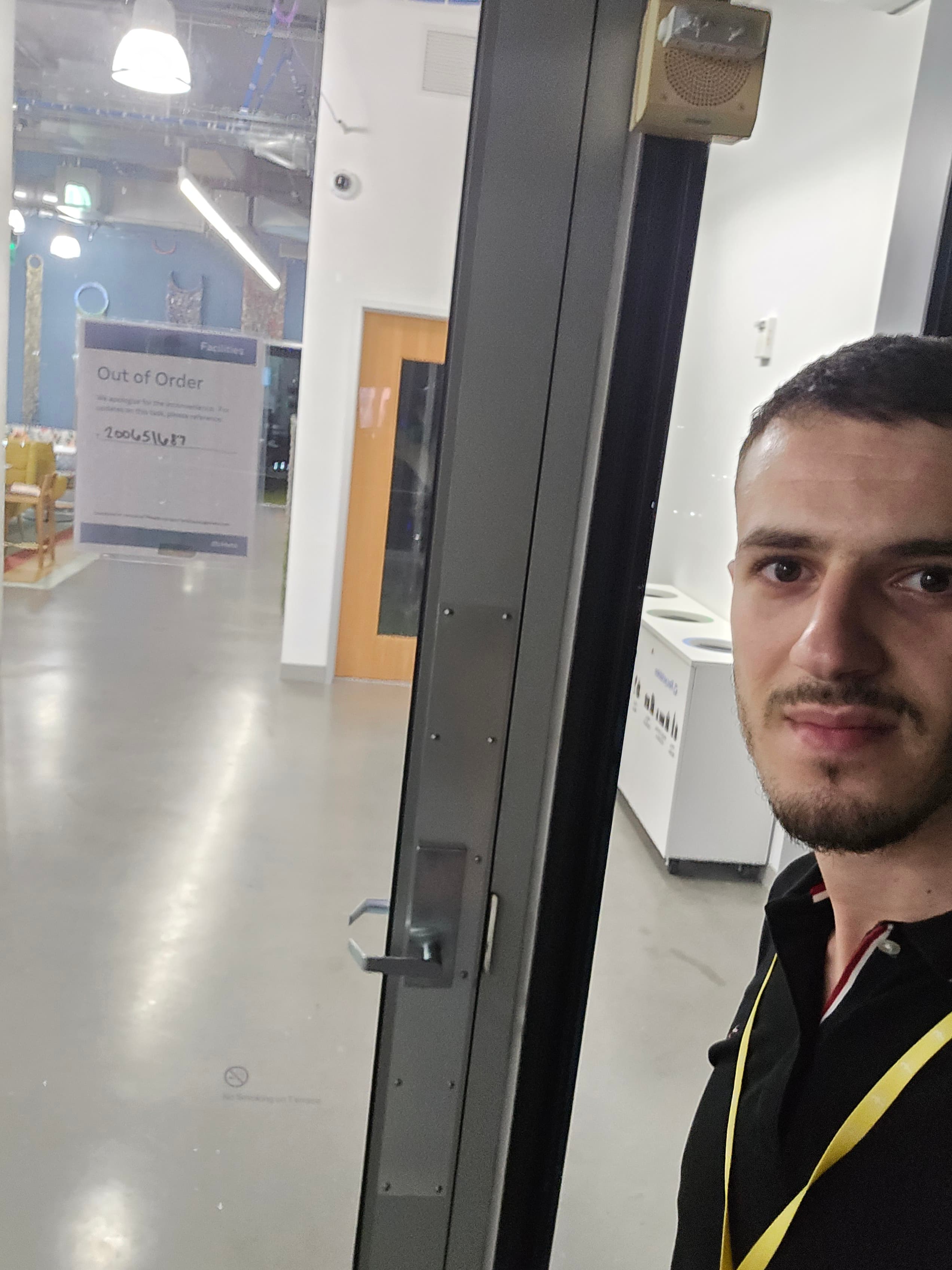 Bearded man looking at camera beside glass door with an "Out of Order" sign.